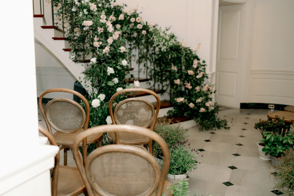 Ceremony set up in front room with stairs inside the Peterloon Estate. Room filled with chairs and floral arrangements. 