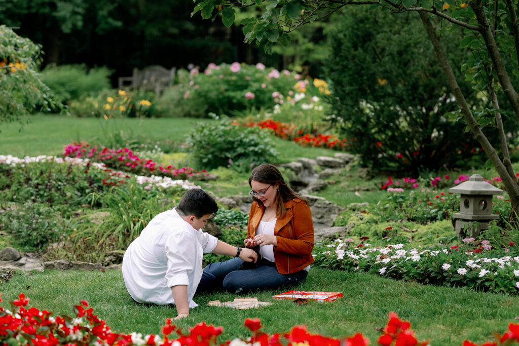 Two women sitting on the ground in a garden playing scrabble.