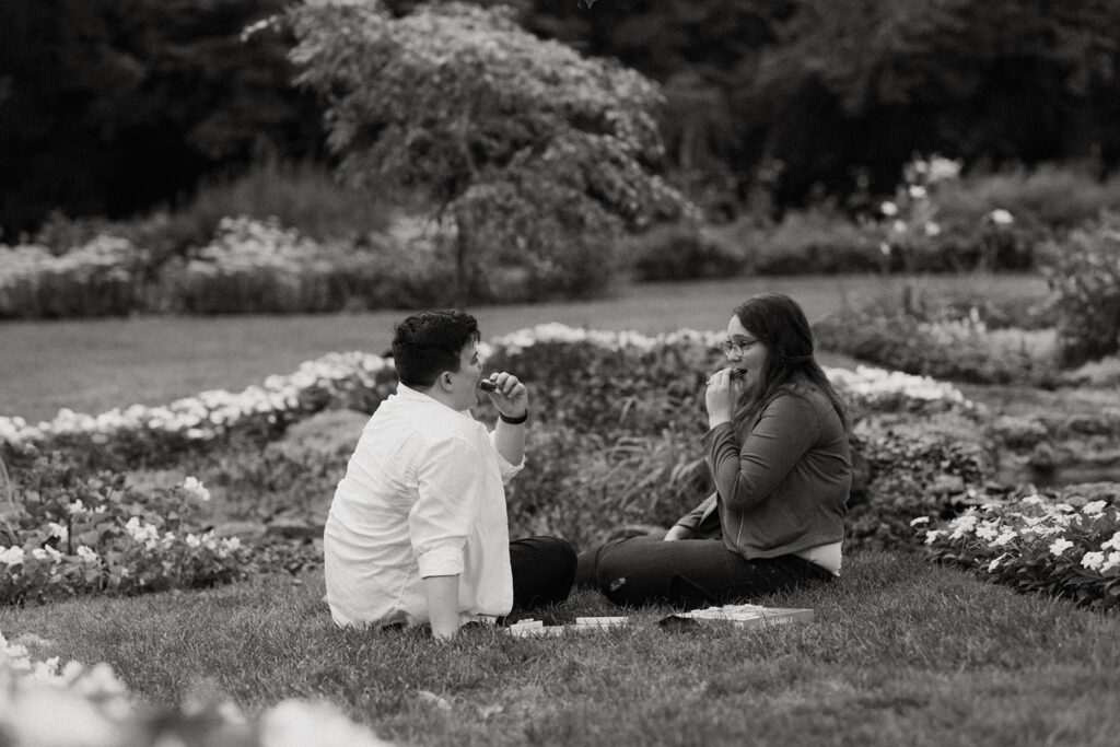 Two women sitting on the ground in a garden playing scrabble.