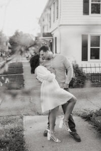 black and white image of couple dancing on a sidewalk during their spring engagement session 